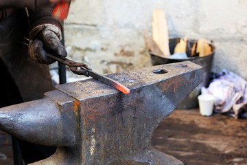 Blacksmith working metal with hammer on the anvil