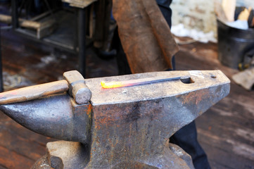 Blacksmith working metal with hammer on the anvil