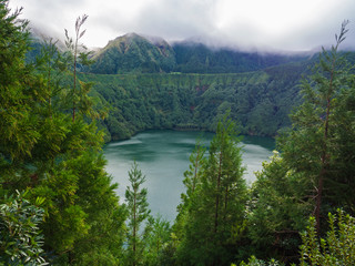 Obraz na płótnie Canvas Beautiful View over Lagoa de Santiago Lake with green trees and hills coved by fog from Miradouro do Cerrado das Freiras, Azores, Sao Miguel