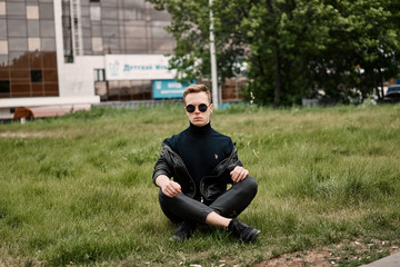 Fototapeta premium man in the hat wears sunglasses sitting on the grass