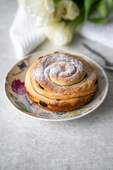 baked bun on a colorful plate, on a marble backdrop, homemade, tulips on background