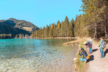 Group of Friends travelers having fun on their vacation in Italian Dolomites Mountains. Dobbiaco lake