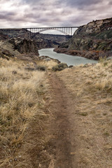 Dirt trail leads to the Snake River in Twin Falls with a arched bridge