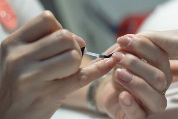 Obraz na płótnie Canvas Manicurist is applying a nail base gel on a female finger nails. Nail care concept.