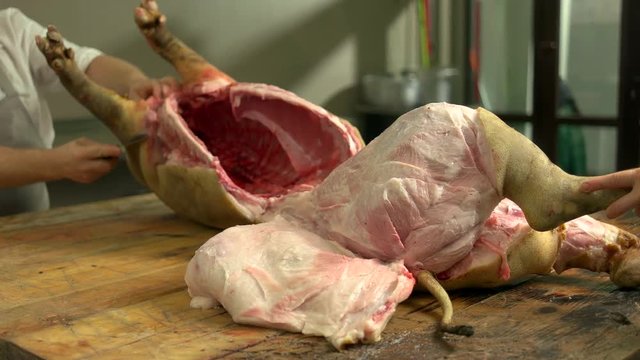 Whole carcass of fresh raw pork on wooden table. Butcher cutting raw pork at meat factory. Pork meat processing rules.