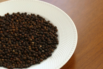 grains of black pepper in white plate