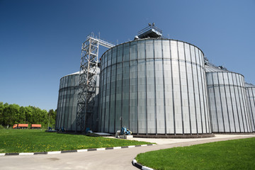 Modern plant for storage and processing crops. Industrial landscape. Big granaries in sunny summer day