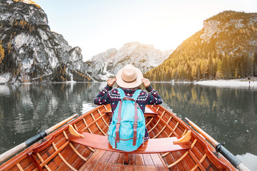 Happy asian woman sitting in wooden vintage boat floating and sailing on a Braies lake in Italian Alps mountains, Travel and dream vacation concept