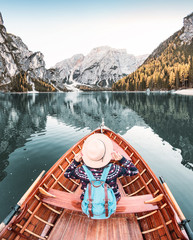 Happy asian woman sitting in wooden vintage boat floating and sailing on a Braies lake in Italian...