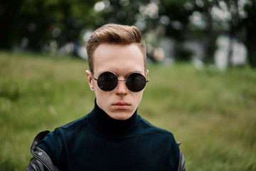 man in the hat wears sunglasses sitting on the grass