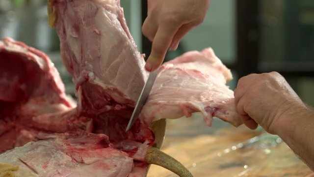 Close up butcher removing the skin from pig leg. Hands of butcher cutting raw pork meat. Processing a pig at home.