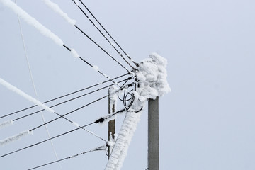 power line on a pole of many wires covered with a thick layer of snow