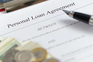 Personal loan agreement  paper form with  pen and money. Defocused business background.