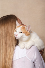 Drowsy sleeping white cat on a woman's shoulder. White cat on the shoulder of a blonde