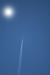 airplane in the sky,sun,light,travel,fly,blue,white,condensation, vapour,transportation, trace, high,