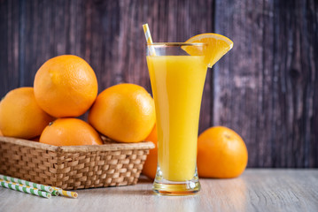 Glass of freshly squeezed orange juice standing on dark background with a fresh oranges