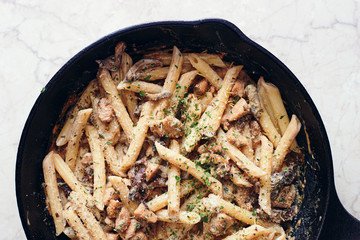 Hot homemade italian creamy pasta with forest mushrooms and chicken fillet in a pan top view