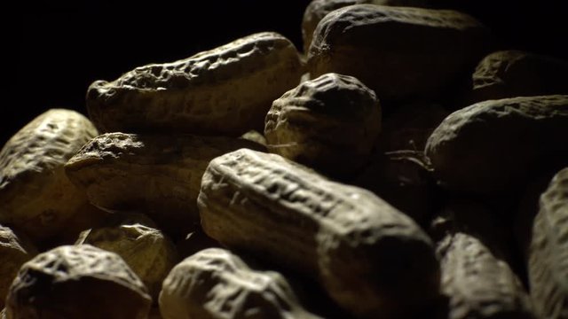 Raw Inshell Peanuts in Rotation. peanuts in shell. Snack closeup.   Peanuts in a bowl. Selective focus. black background. Studio shot. Healthy food concept.