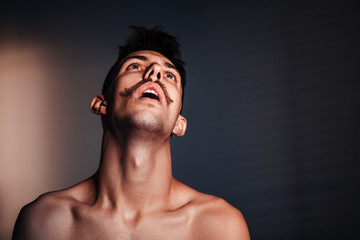 Fototapeta premium Young shirtless man in despair by the window