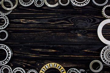 Bearings on wooden black background with empty space for text in the center.