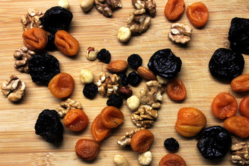 Dried fruits and nuts on wooden background scattered