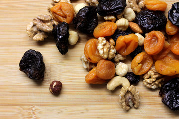 Dried fruits and nuts on wooden background scattered
