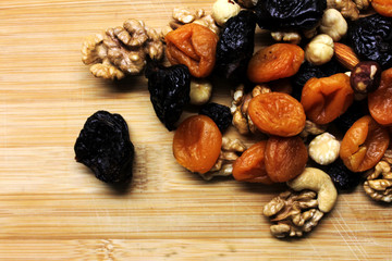 Dried fruits and nuts on wooden background scattered