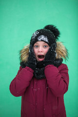 Cute girl yells in surprise in winter near the wall.