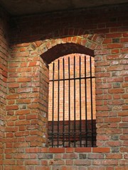 Historical Arched Window with Iron Bars on Red Brick Wall