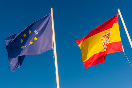 EU and Spanish flags side by side. Europe Union flag.  Blue skies on the background.