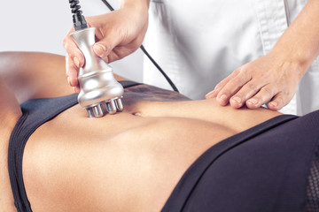 The doctor does the Rf lifting procedure on the stomach and hips of a woman in a beauty parlor....