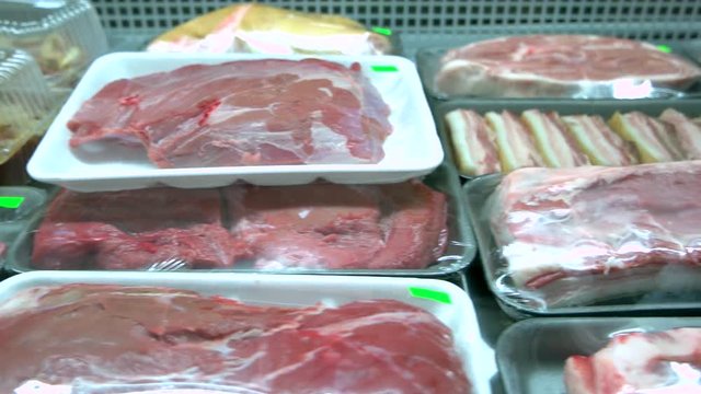 Shelves with fresh meat at supermarket. Assortment of raw meat at butchers shop. Organic meat store.
