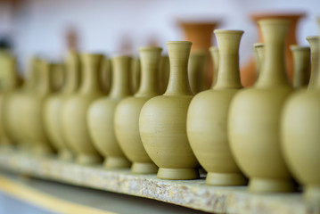 Fototapeta na wymiar Just made pottery in clay workshop. Row of handmade jugs, selective focus