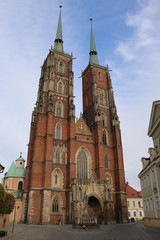 Obraz premium Historic, gothic Cathedral of St. John the Baptist in Wroclaw. A beautiful, medieval basilica with two towers. A brick, Catholic church on the island of Ostrów Tumski. View of the facade during spring