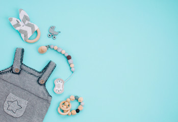 Baby romper, soother and wooden toys on blue background