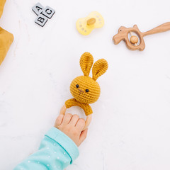 Kids hand holding bunny beanbag on light marble background