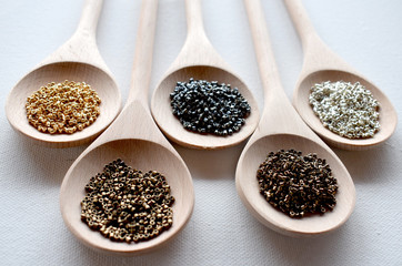 Wooden spoons full of seed beads on a white background