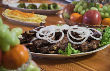 Overhead view of colorful roast vegetables, savory sauces and salt served with grilled t-bone steak on a rustic wooden counter in a country steakhouse