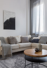Abstract black and white painting above corner sofa in grey living room
