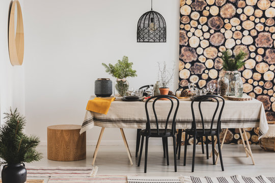 Forest inspired dining room with wooden wallpaper and stylish black chandelier
