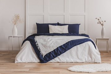 White pillow on blue bedding on king size bed in fashionable bedroom interior