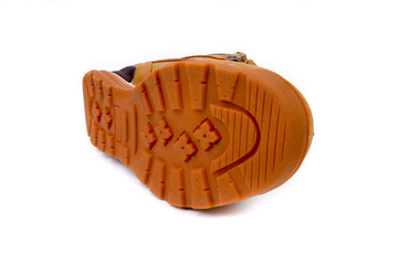 Tan brown boots closeup with rude rubber sole on white background. Horizontal shot. Left leg. Very close-up of fingertip. Classic, new boots.