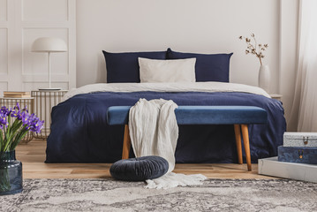 White pillow on blue bedding on king size bed in fashionable bedroom interior