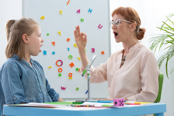 Speech therapist and girl learning vowels