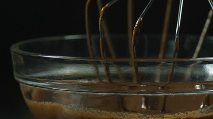Liquid chocolate. Mixing melted liquid premium dark chocolate with a big whisk in a glass container. Confectionery. A confectioner prepares a dessert, sauce.