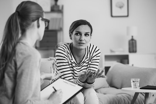 Confused young woman with social problem during psychologist meeting , black and white photo
