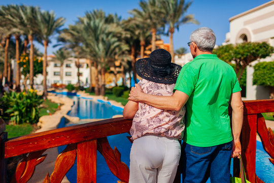 Senior couple relaxing by swimming pool on hotel territory. People enjoying vacation. Valentine's day