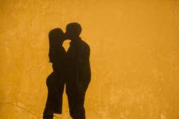 silhouettes of kissing people against a wall