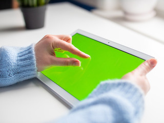 Woman hold tablet in hand with green screen and tap finger on screen. Close up yuang girl  shopping online.