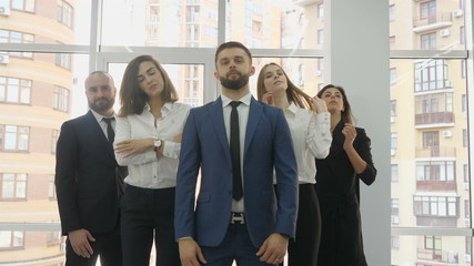 Office workers, two young men and three young women lined up in a triangle presenting themselves as...